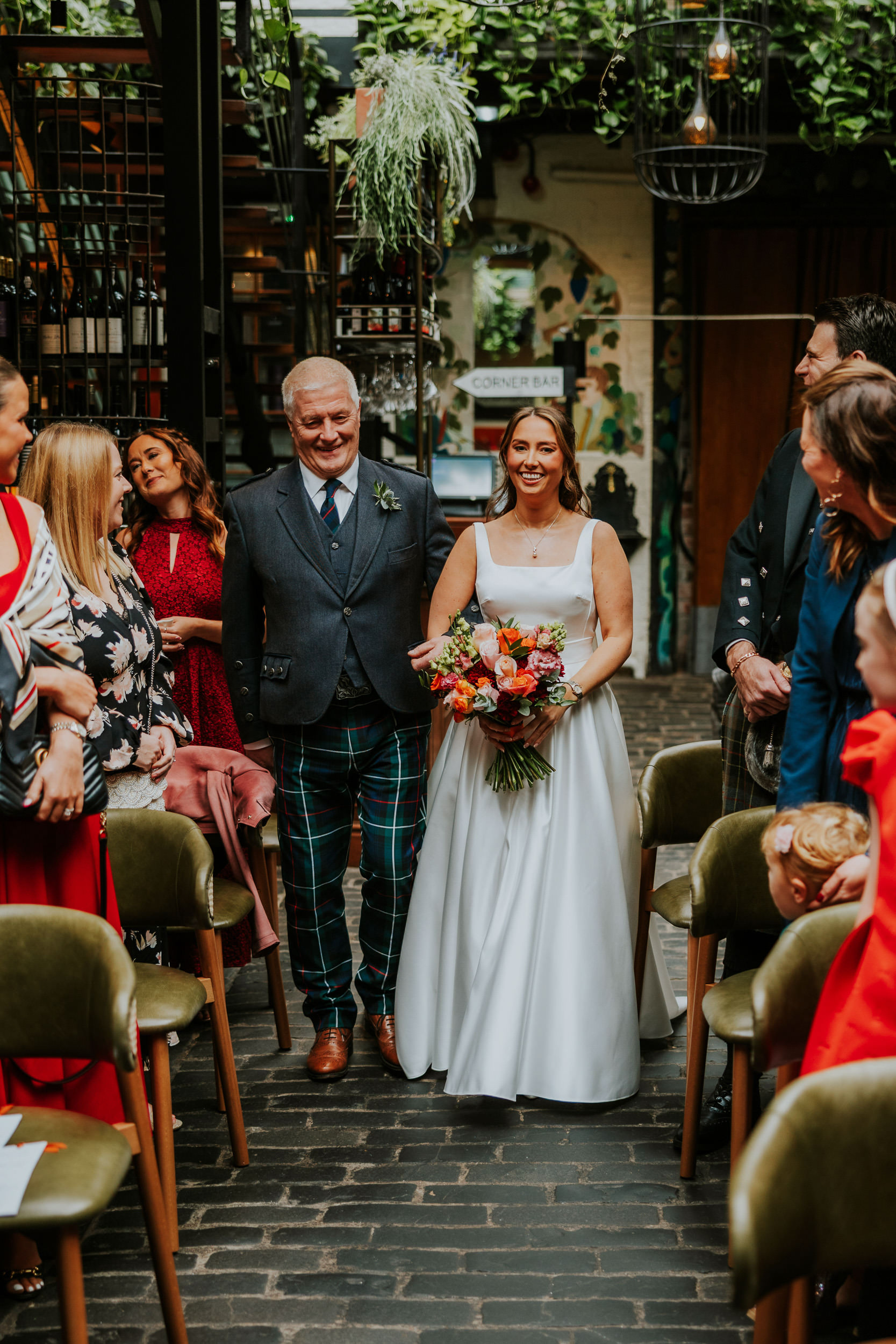 Wedding ceremony at Ubiquitous Chip in Glasgow with the Bride and her dad walking down the aisle 