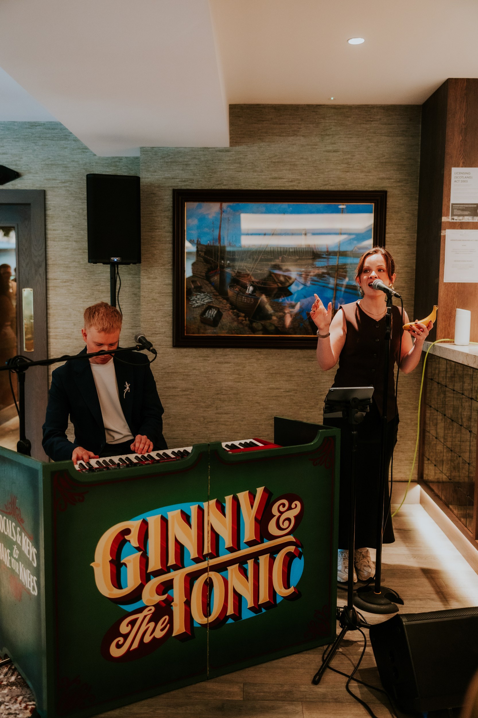 Male keyboard player and female singer performing indoors; singer holds a banana while singing into a microphone.
