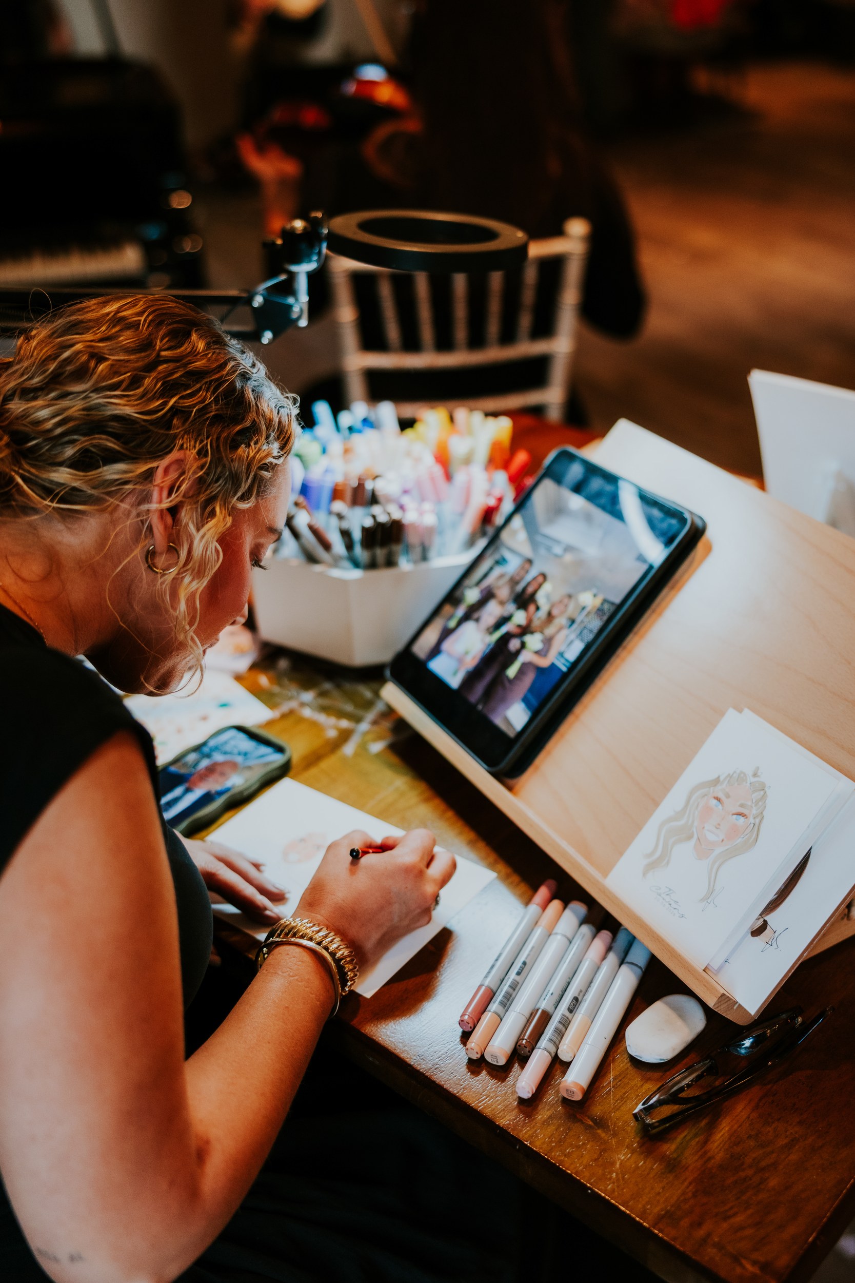 Citation Glasgow wedding photographer 64 Artist sketching wedding guest portraits at a table with markers and an iPad showing a reference photo.
