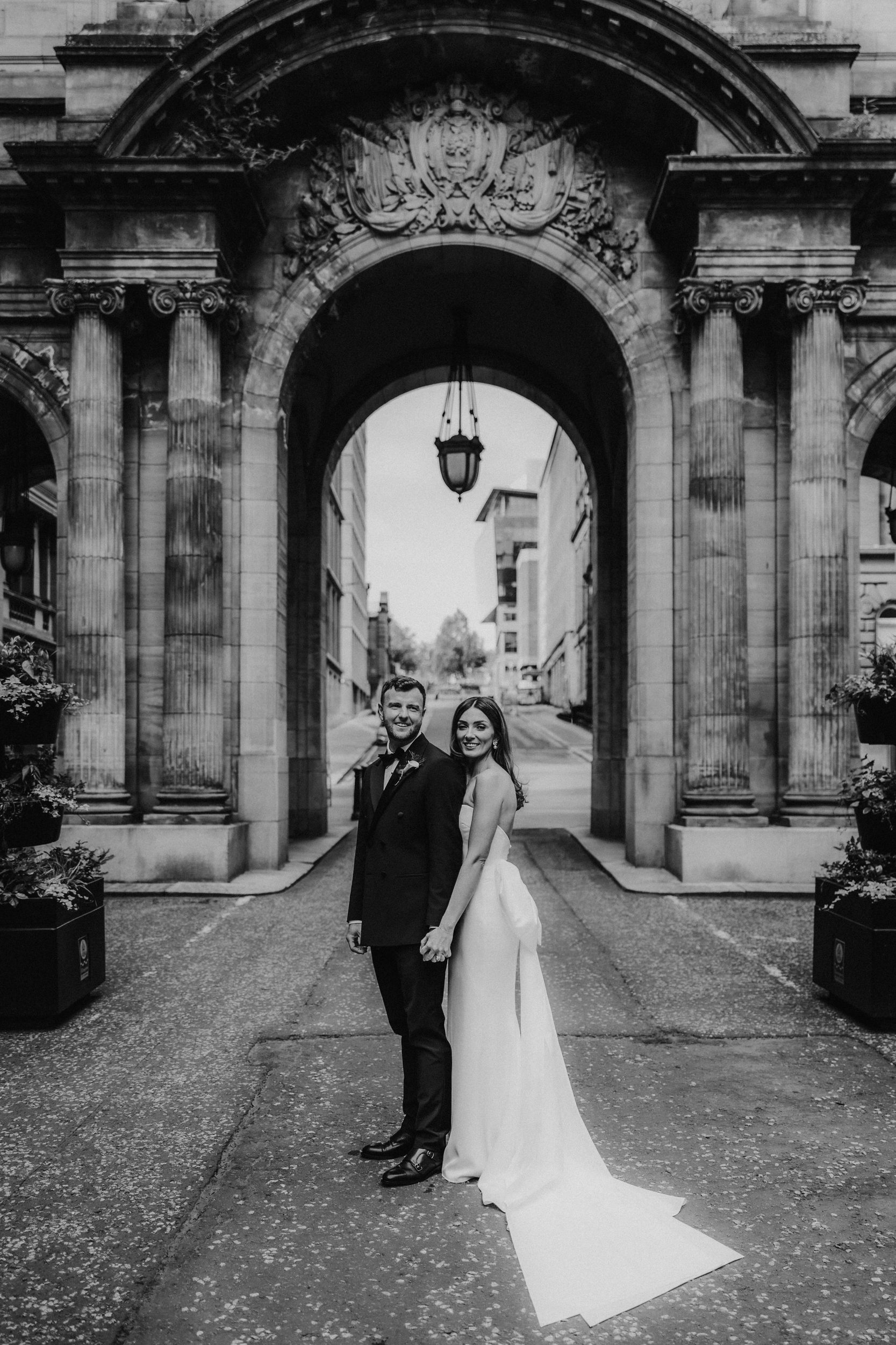 Citation Glasgow wedding photographer 53 Bride and groom holding hands beneath a stone arched entrance at Citation Glasgow, Glasgow.