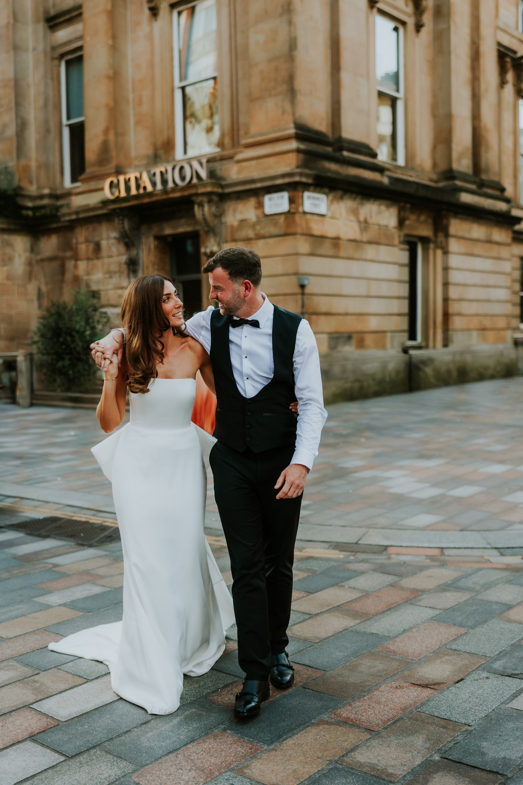 Citation Glasgow wedding photographer 93 Bride and groom walking arm‑in‑arm outside the Citation Glasgow building.