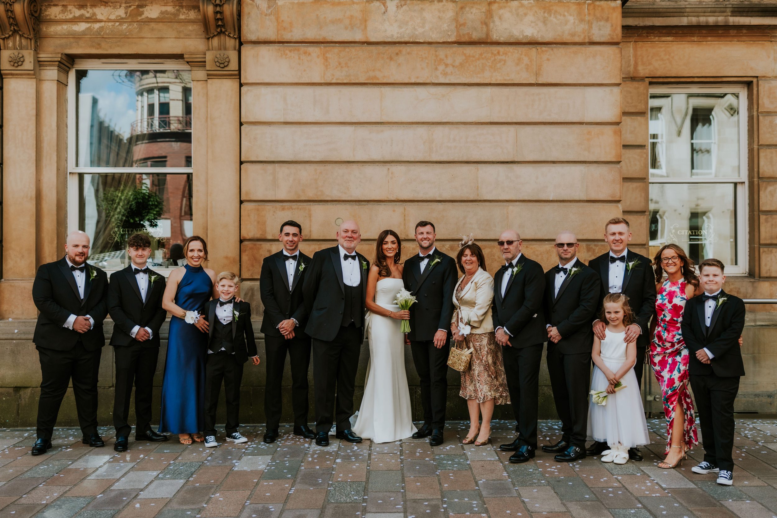 Citation Glasgow wedding photographer 44 Bride in white and groom in tux with wedding party and family lined up outside Citation Glasgow, confetti on the pavement.