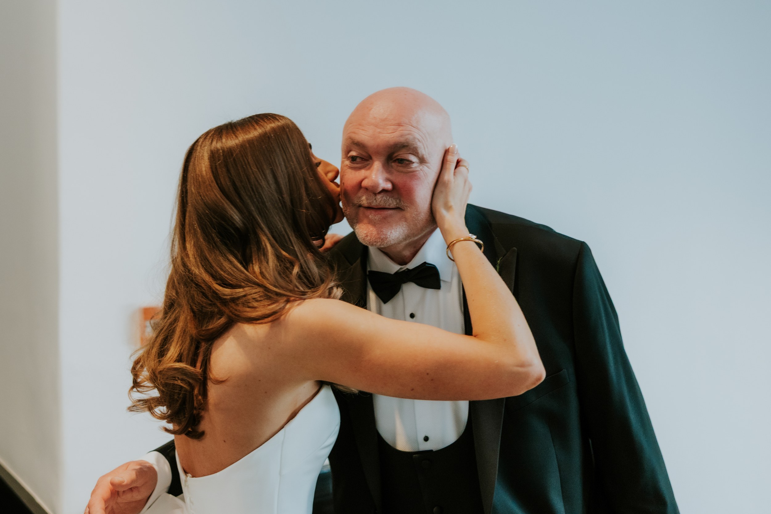 Citation Glasgow wedding photographer 17 Bride kissing an older man in a tuxedo on the cheek, holding his face.