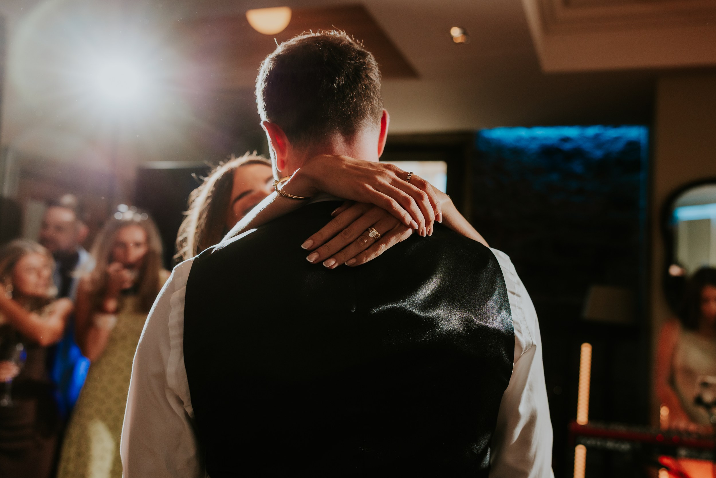 Citation Glasgow wedding photographer 77 Bride's arms and rings around groom's neck as they dance, guests blurred in the background.