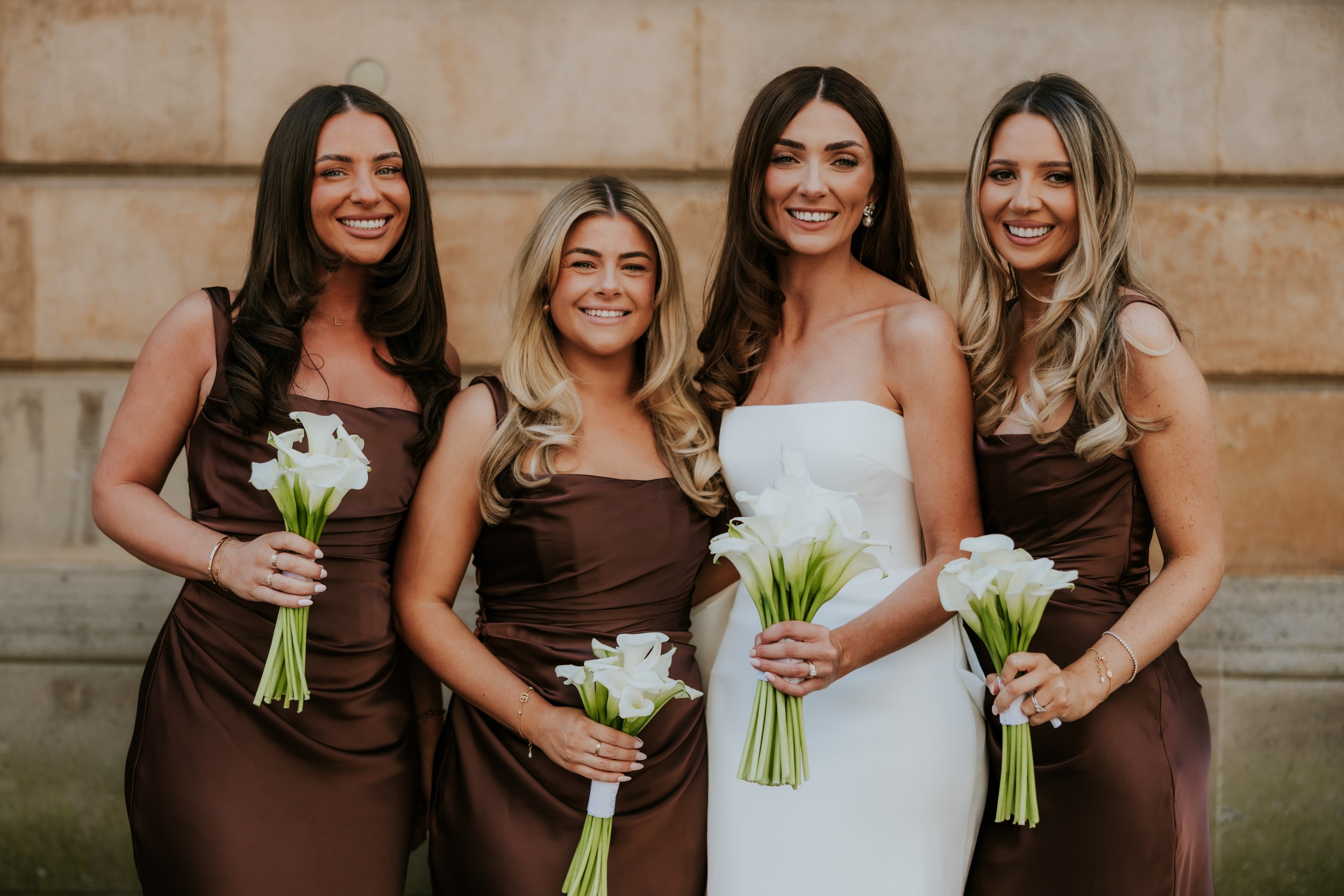 Citation Glasgow wedding photographer 45 Bride with three bridesmaids in brown dresses holding white calla lilies outside a stone building.