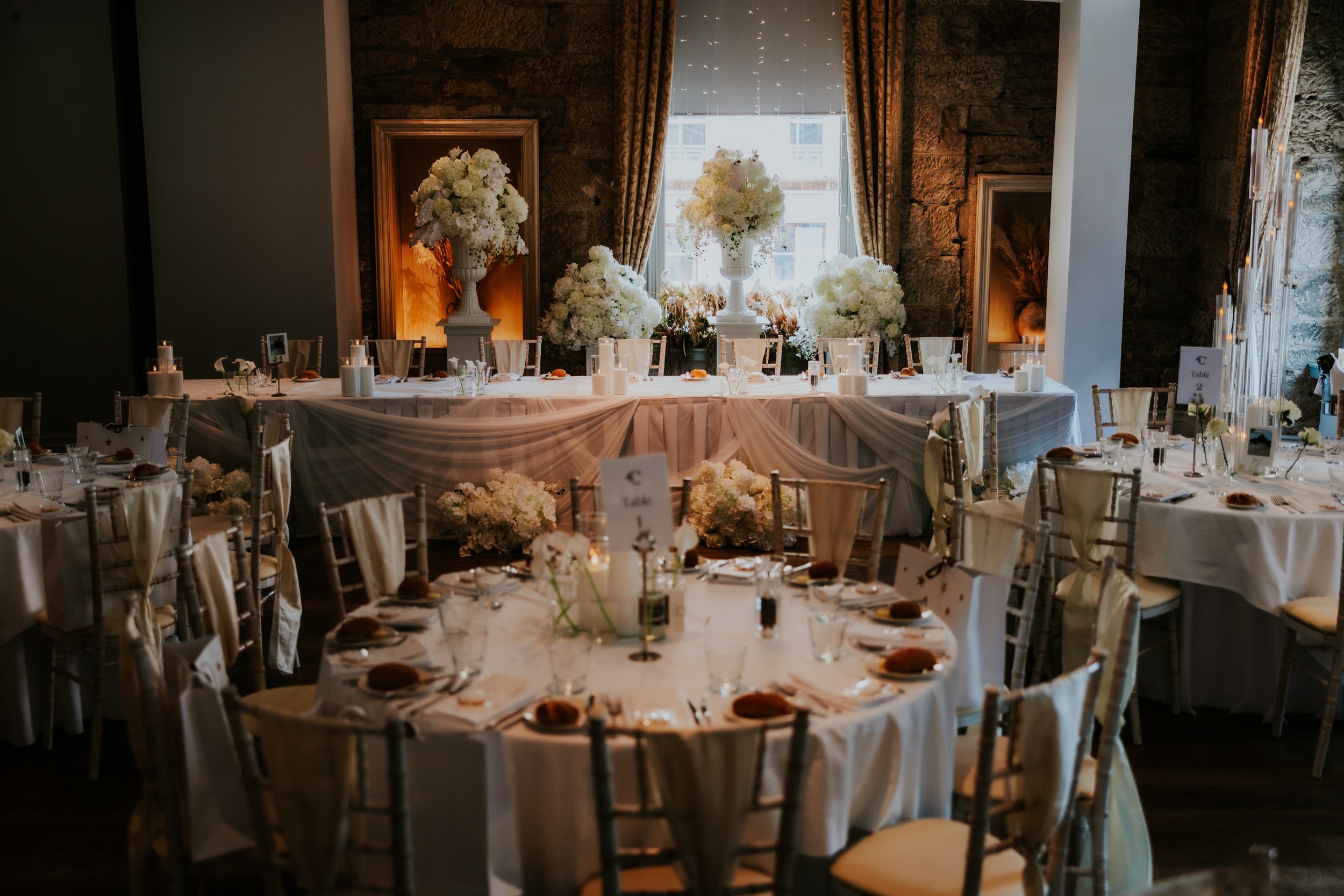 Citation Glasgow wedding photographer 62 Dressed reception room at Citation Glasgow with draped head table, large white floral centrepieces and round guest tables.