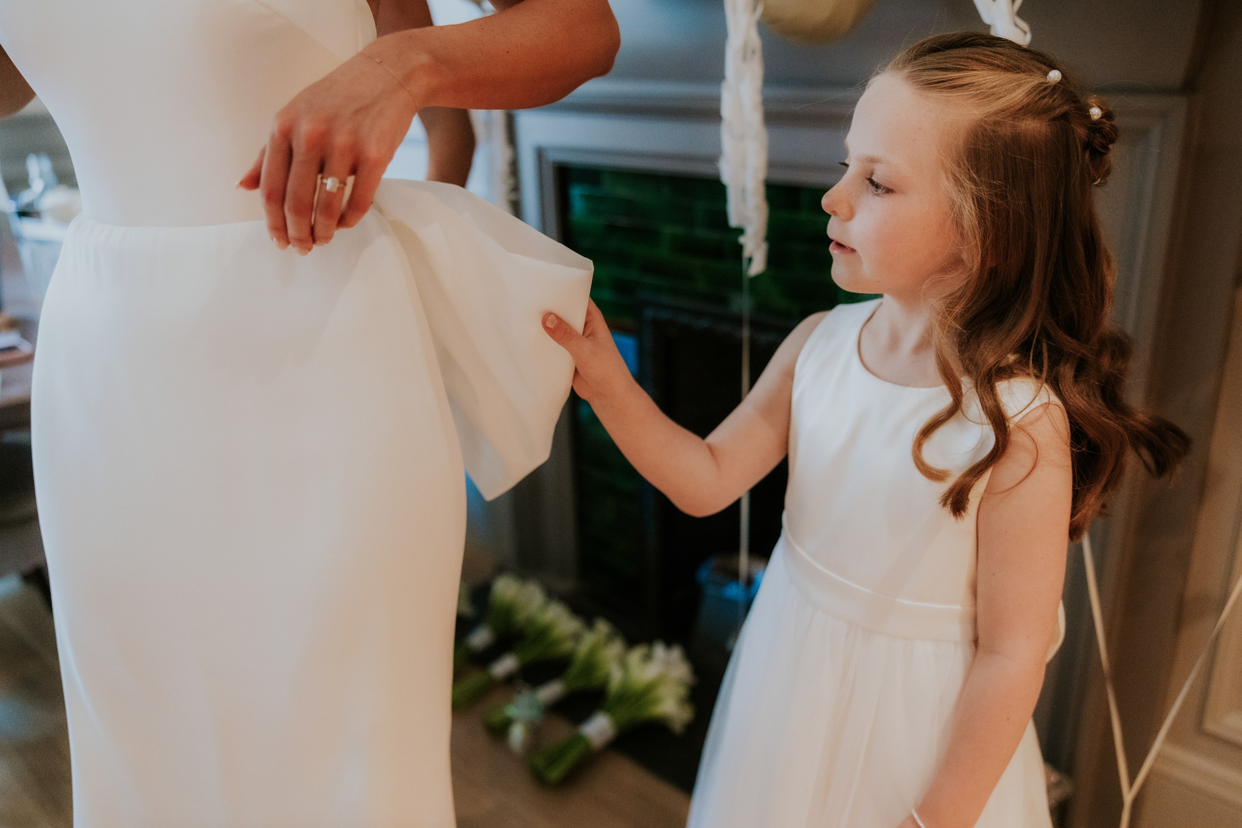Citation Glasgow wedding photographer 15 Flower girl holds the bride's white dress beside an indoor fireplace