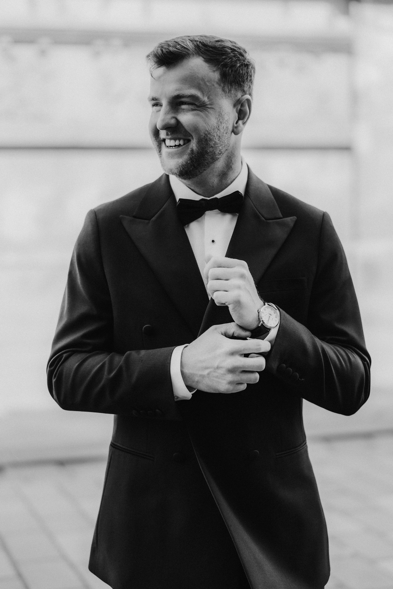 Citation Glasgow wedding photographer 5 Groom in tuxedo and bow tie smiling while adjusting his watch.
