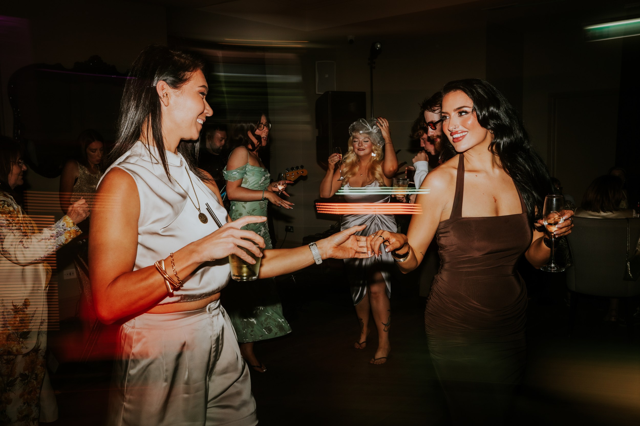 Citation Glasgow wedding photographer 85 Guests dancing at a wedding reception, two women holding hands and drinks with light trails and motion blur.