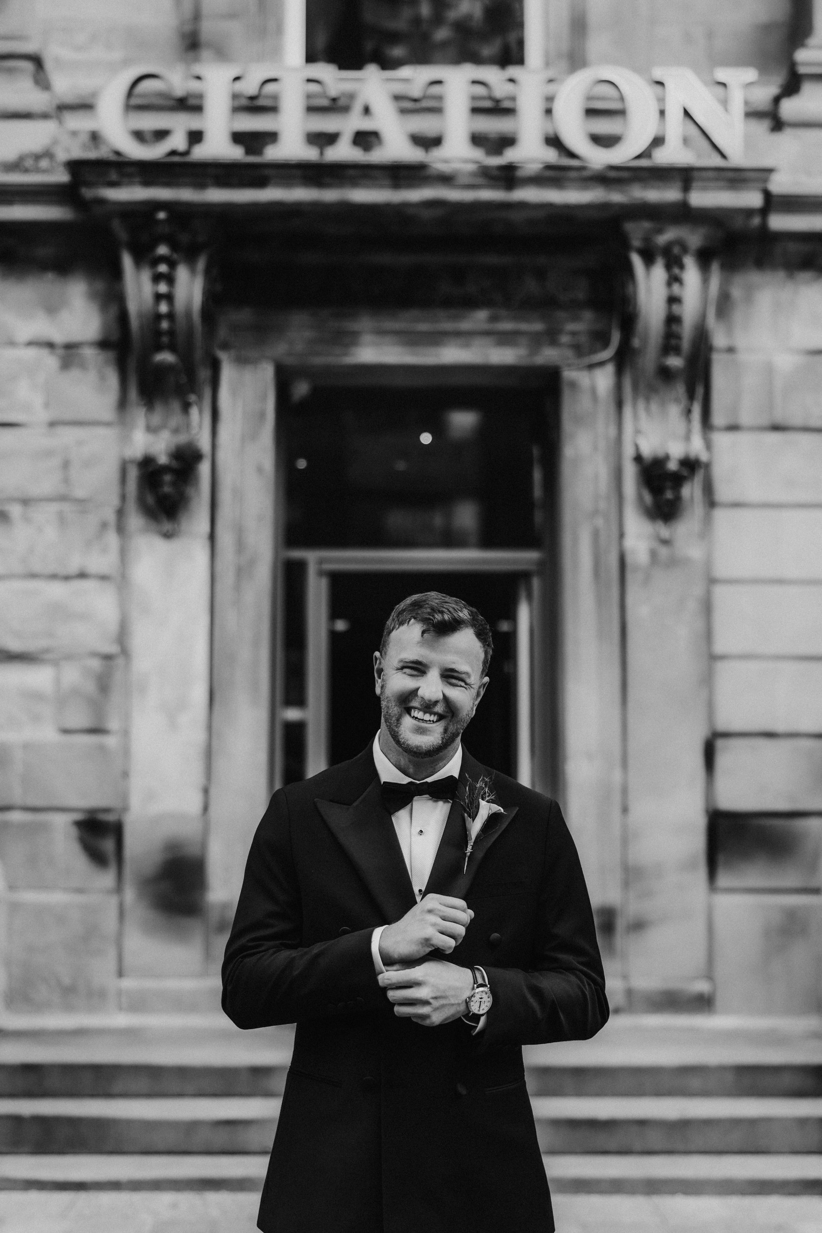Citation Glasgow wedding photographer 11 Smiling groom in a tuxedo standing outside the Citation Glasgow entrance.