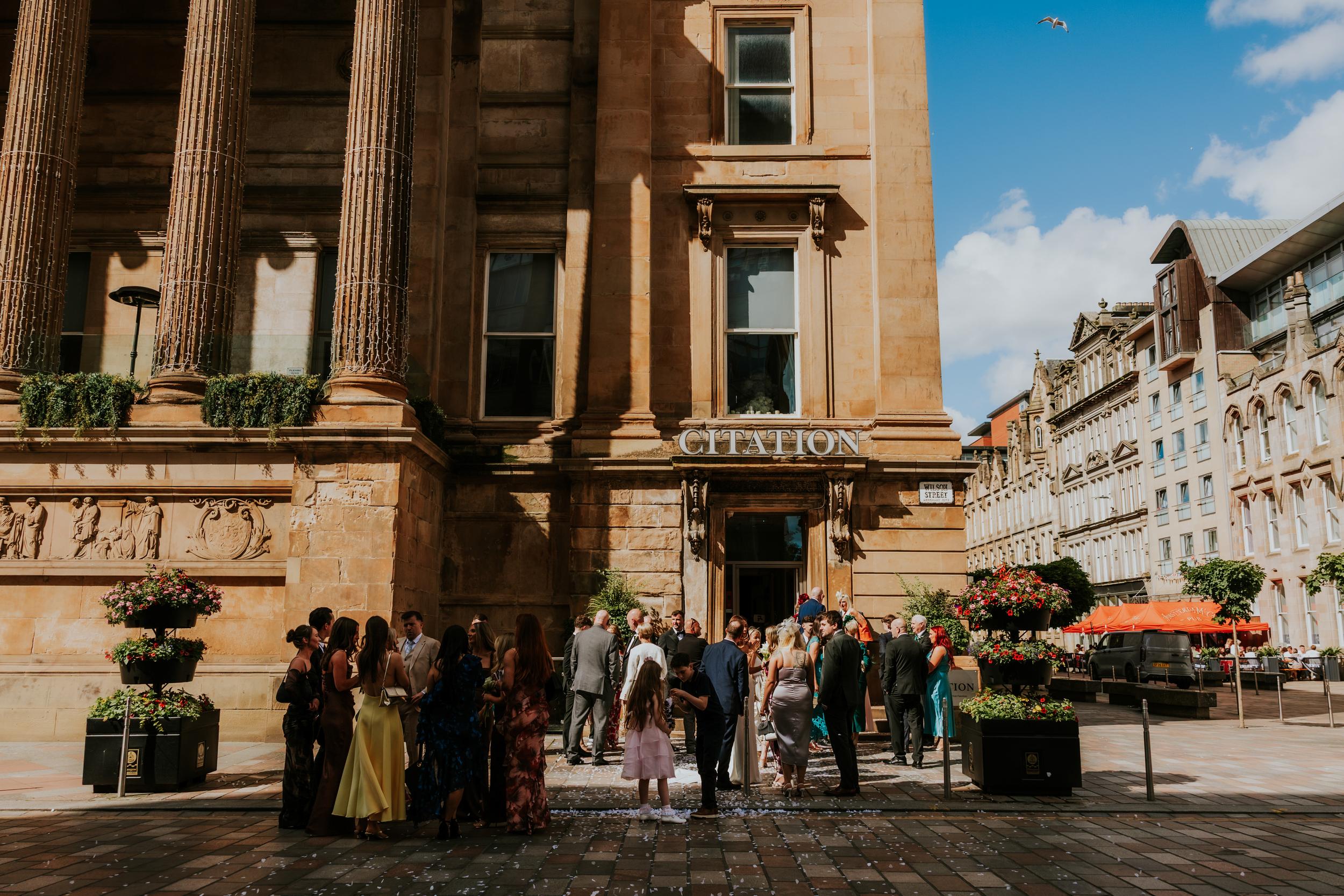 Citation Glasgow wedding photographer 43 Wedding guests gathered outside the Citation Glasgow entrance with confetti on the pavement.