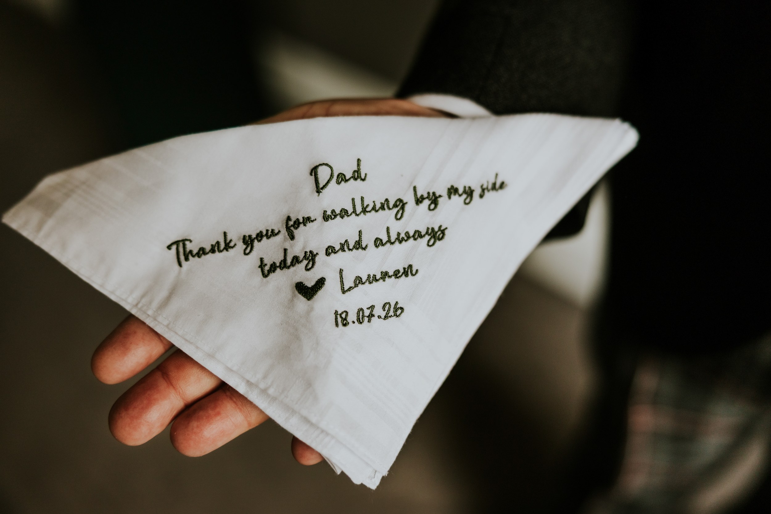White handkerchief embroidered 'Dad
Thank you for walking by my side
Lauren 18.07.26' held in a hand.