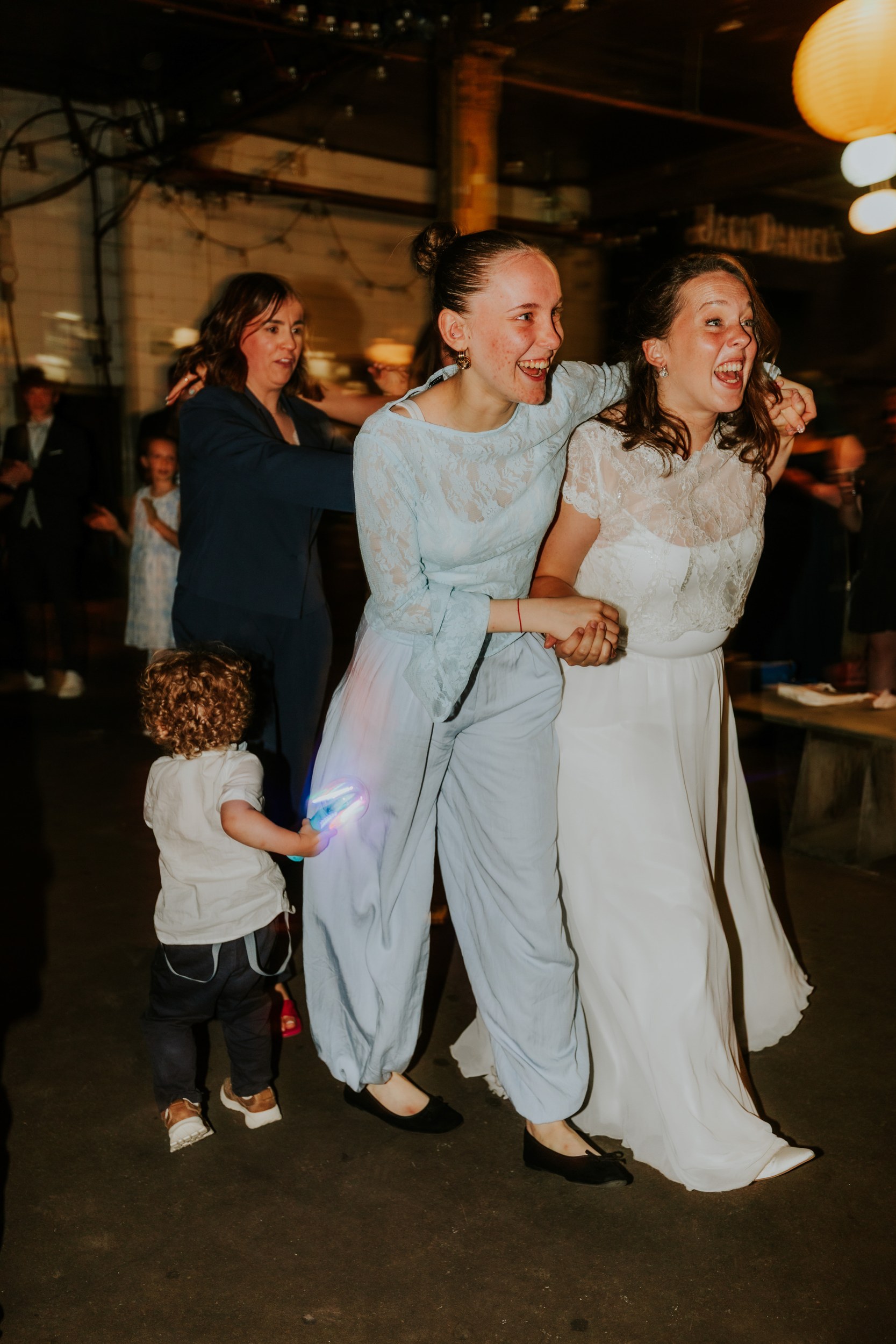 Daniel & Natalie’s Wedding at The Biscuit Factory 75 Natalie and a guest laughing with linked arms on the dance floor.