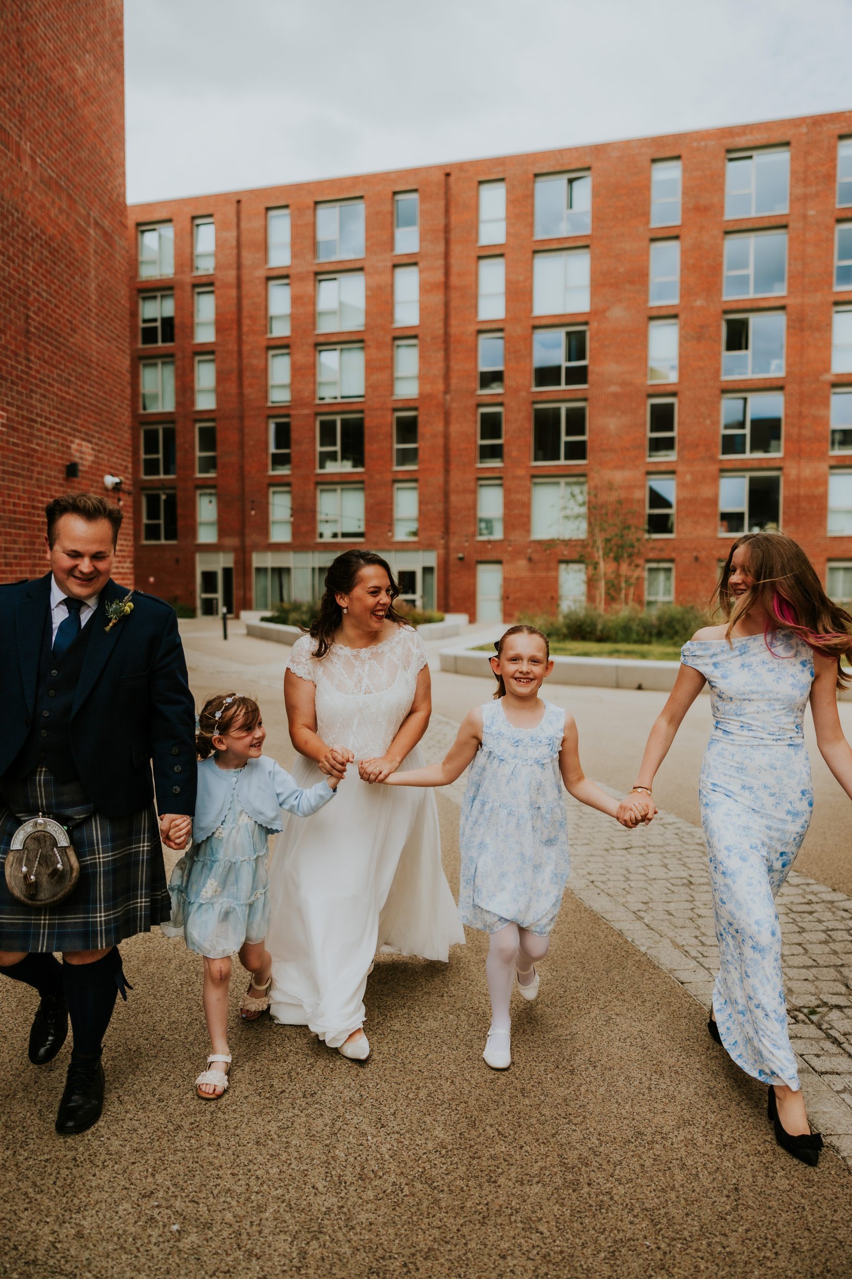 Daniel & Natalie’s Wedding at The Biscuit Factory 41 Natalie and Daniel walking outside The Biscuit Factory with three attendants holding bouquets.