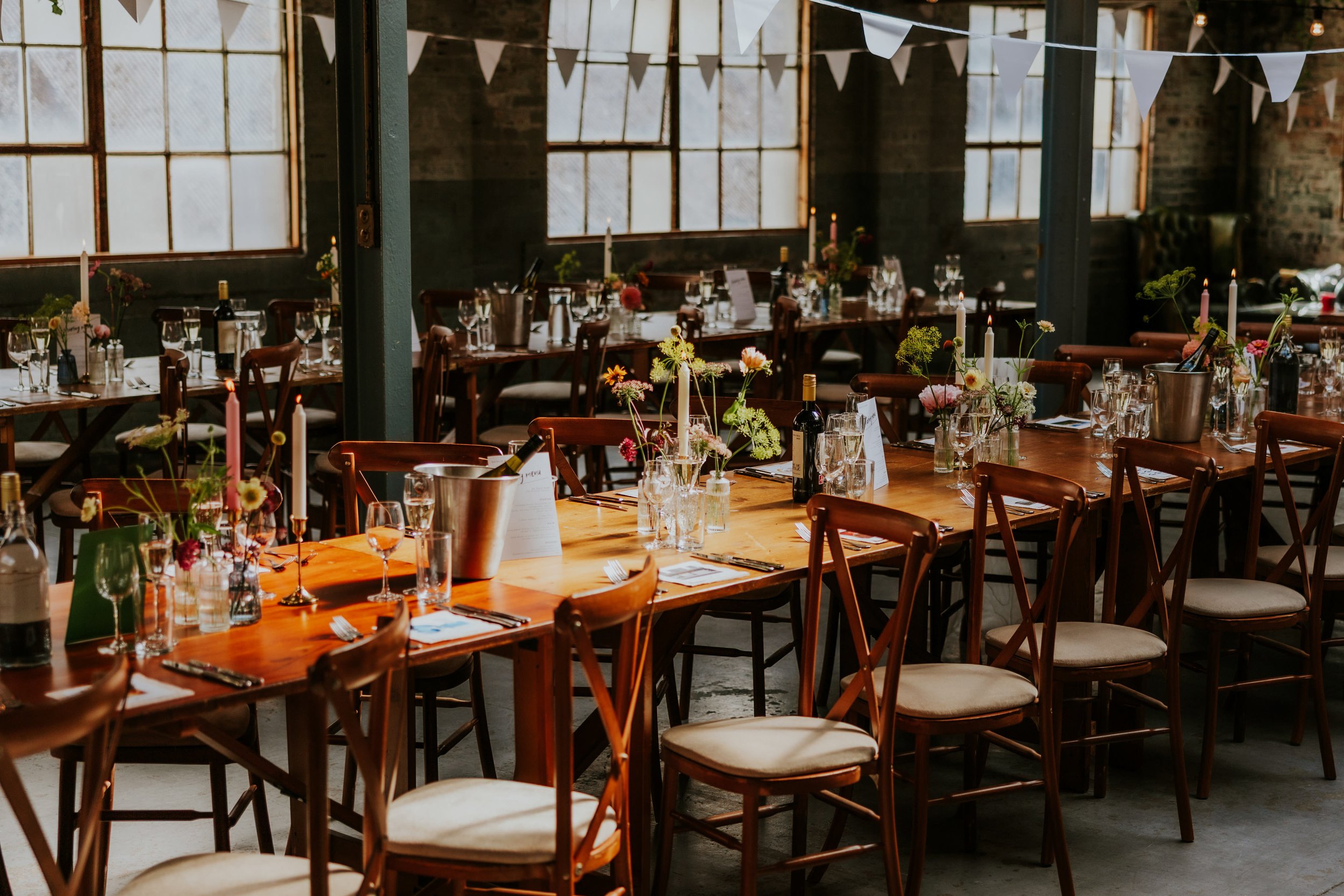 Daniel & Natalie’s Wedding at The Biscuit Factory 52 Wedding reception tables at The Biscuit Factory, Edinburgh with candles, flowers, wine and glassware in an industrial room