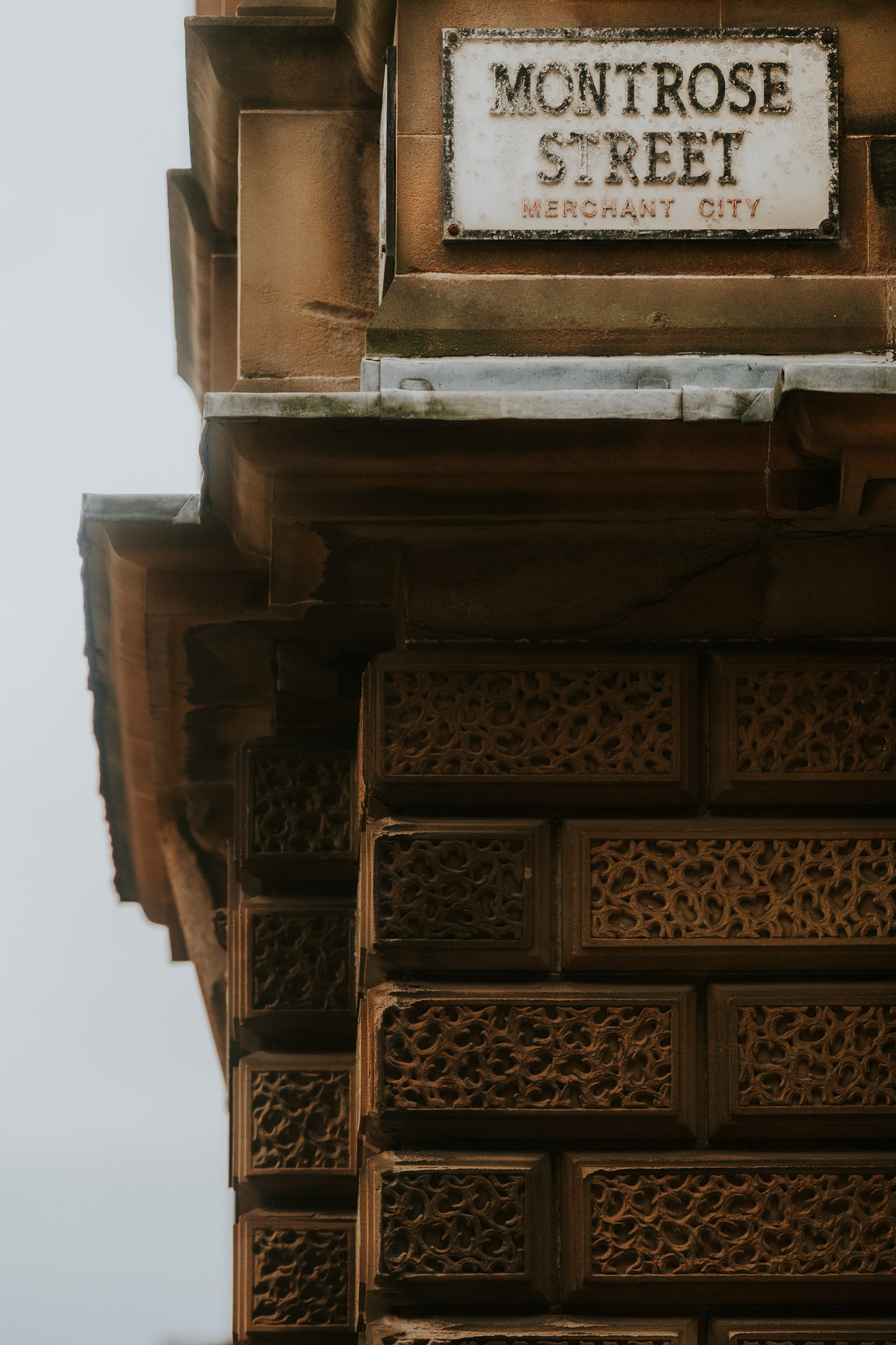 Alana & Kyle’s Glasgow Wedding — City Centre to The Bothy 2 Sandstone building corner with carved block details and a 'Montrose Street, Merchant City' sign.