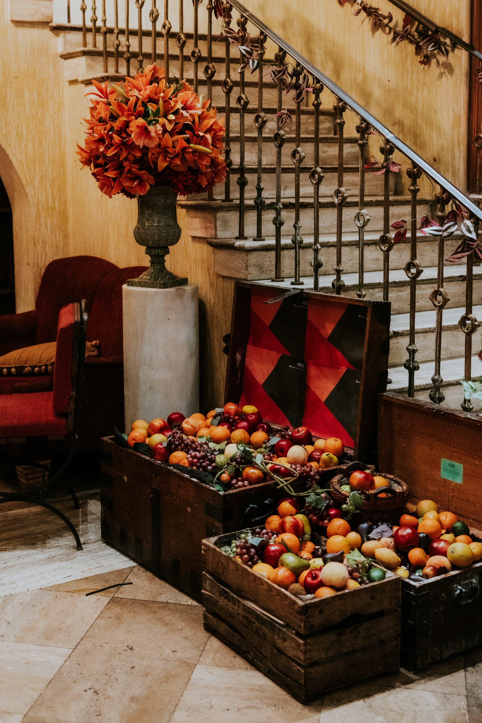 Fruit-filled wooden crates and orange flowers beside the ornate staircase at Arta, Glasgow.
