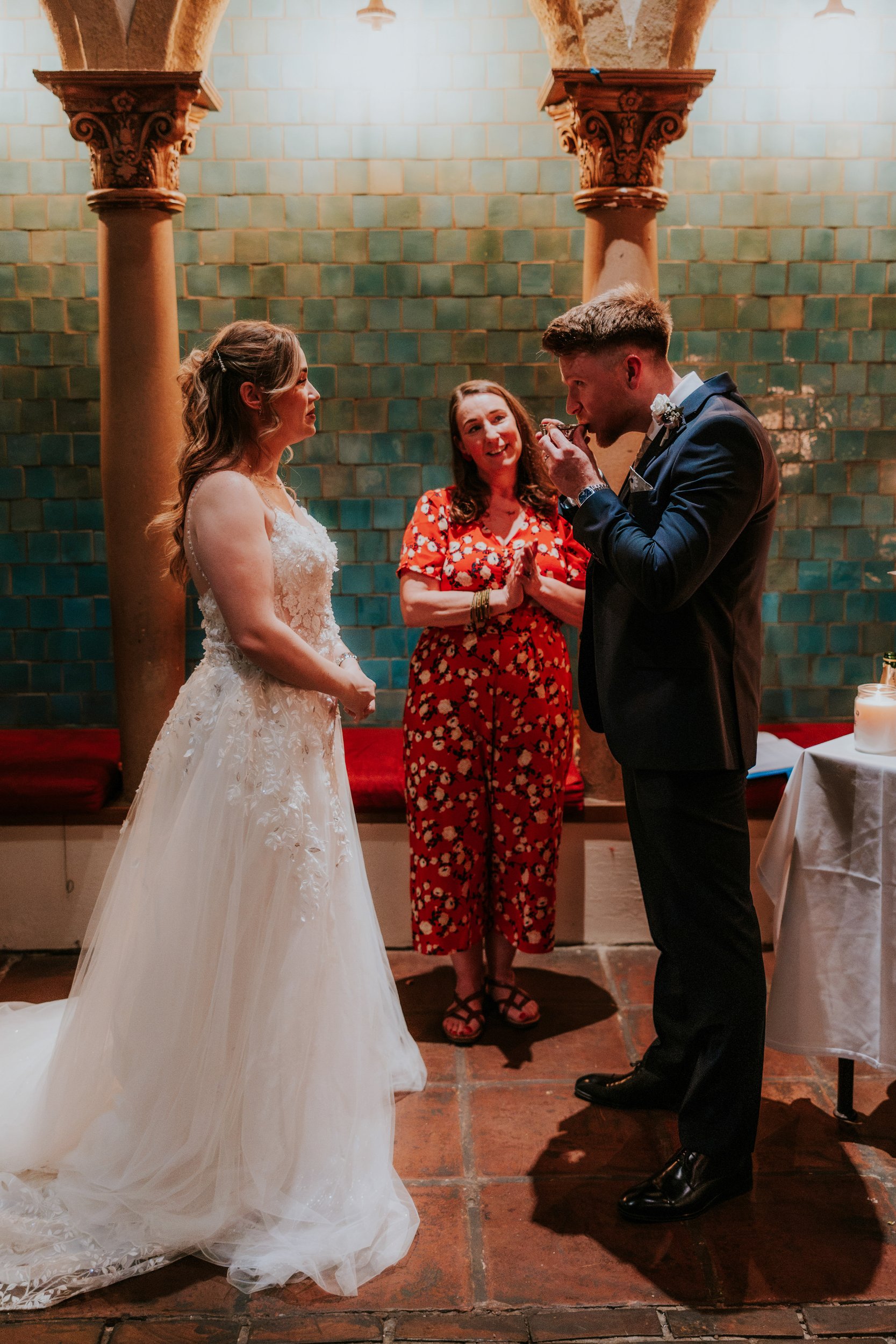 John drinks from a quaich as Lucy and the celebrant watch during their wedding ceremony at Arta, Glasgow.