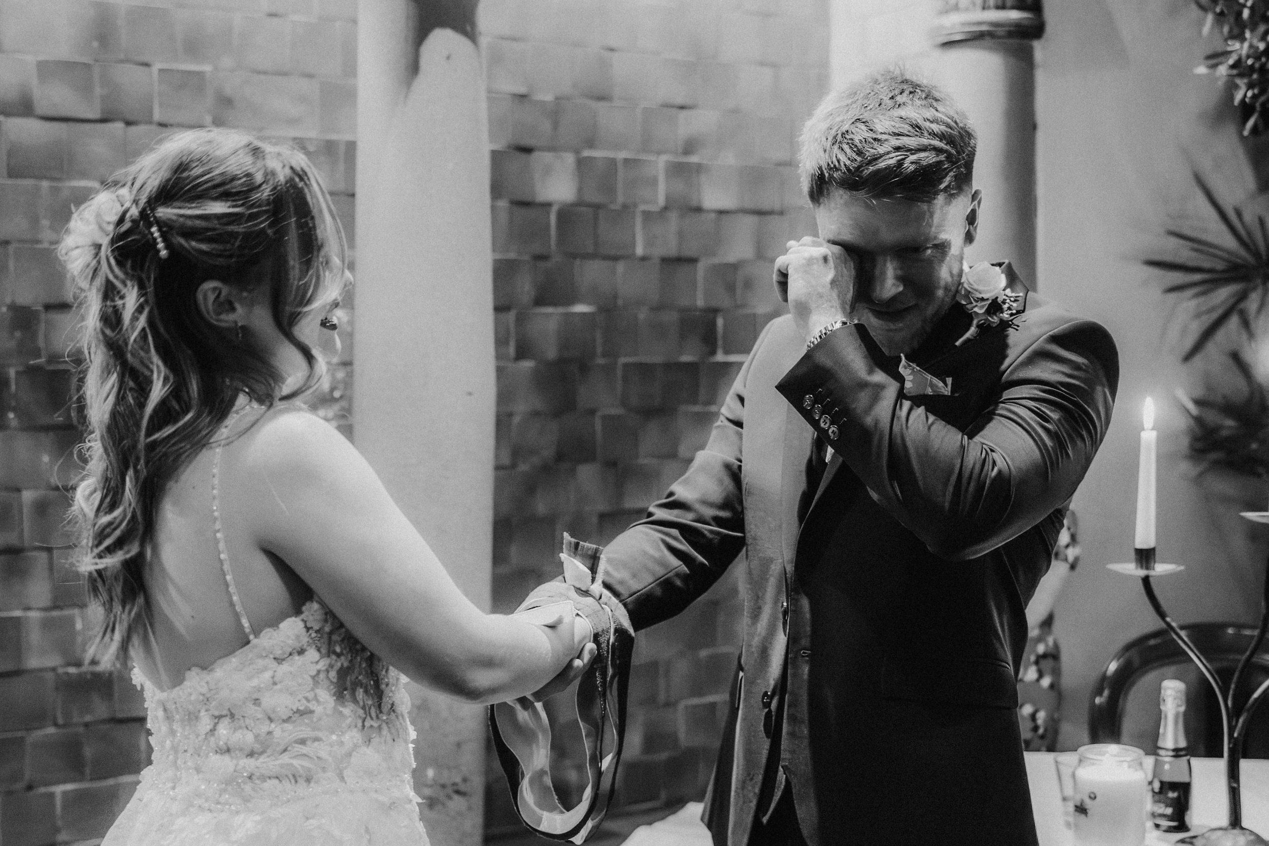 John wipes his eye while holding Lucy's hand during their handfasting ceremony at Arta, Glasgow.