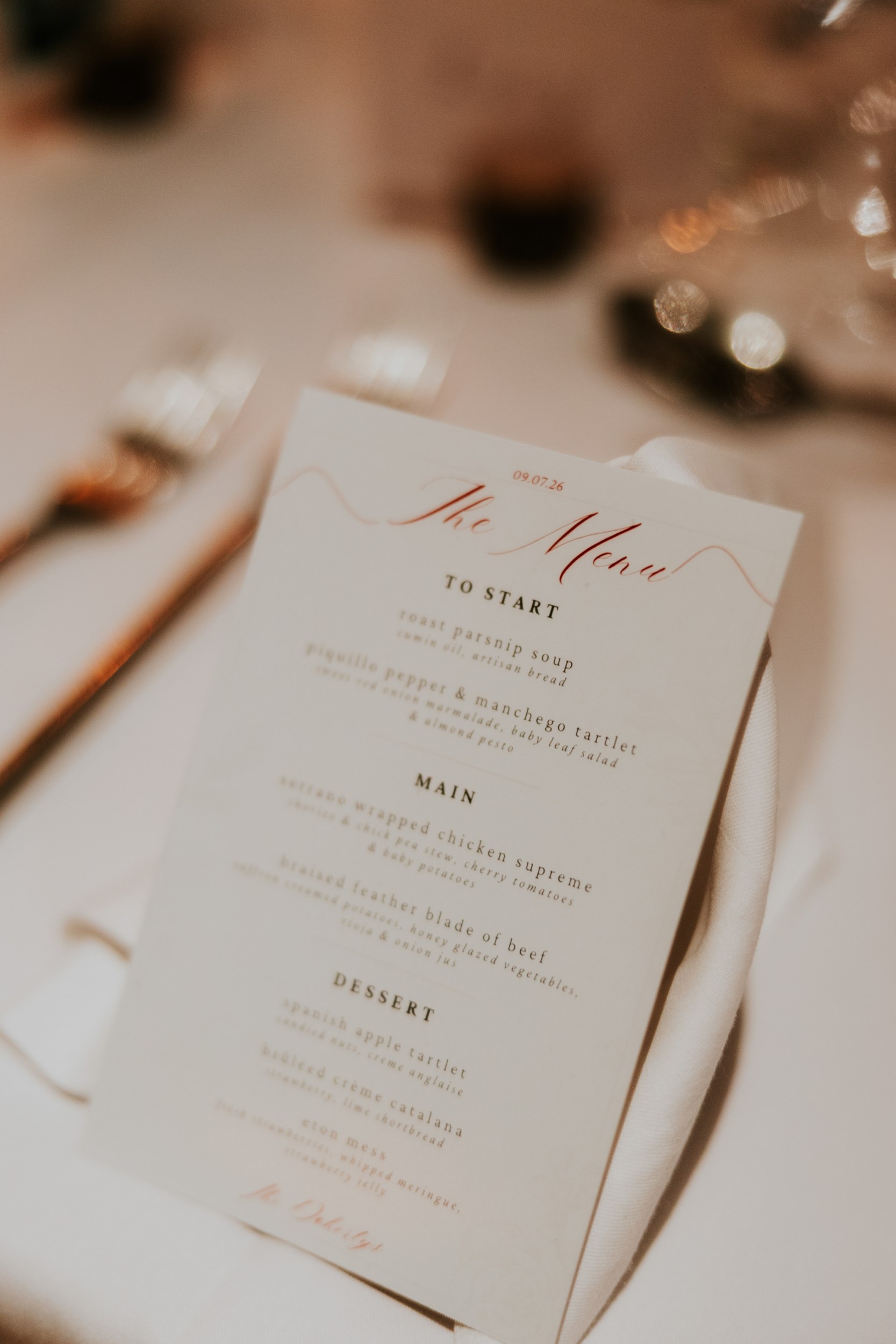 Lucy and John's wedding menu on a folded napkin beside cutlery and glassware at Arta, Glasgow.