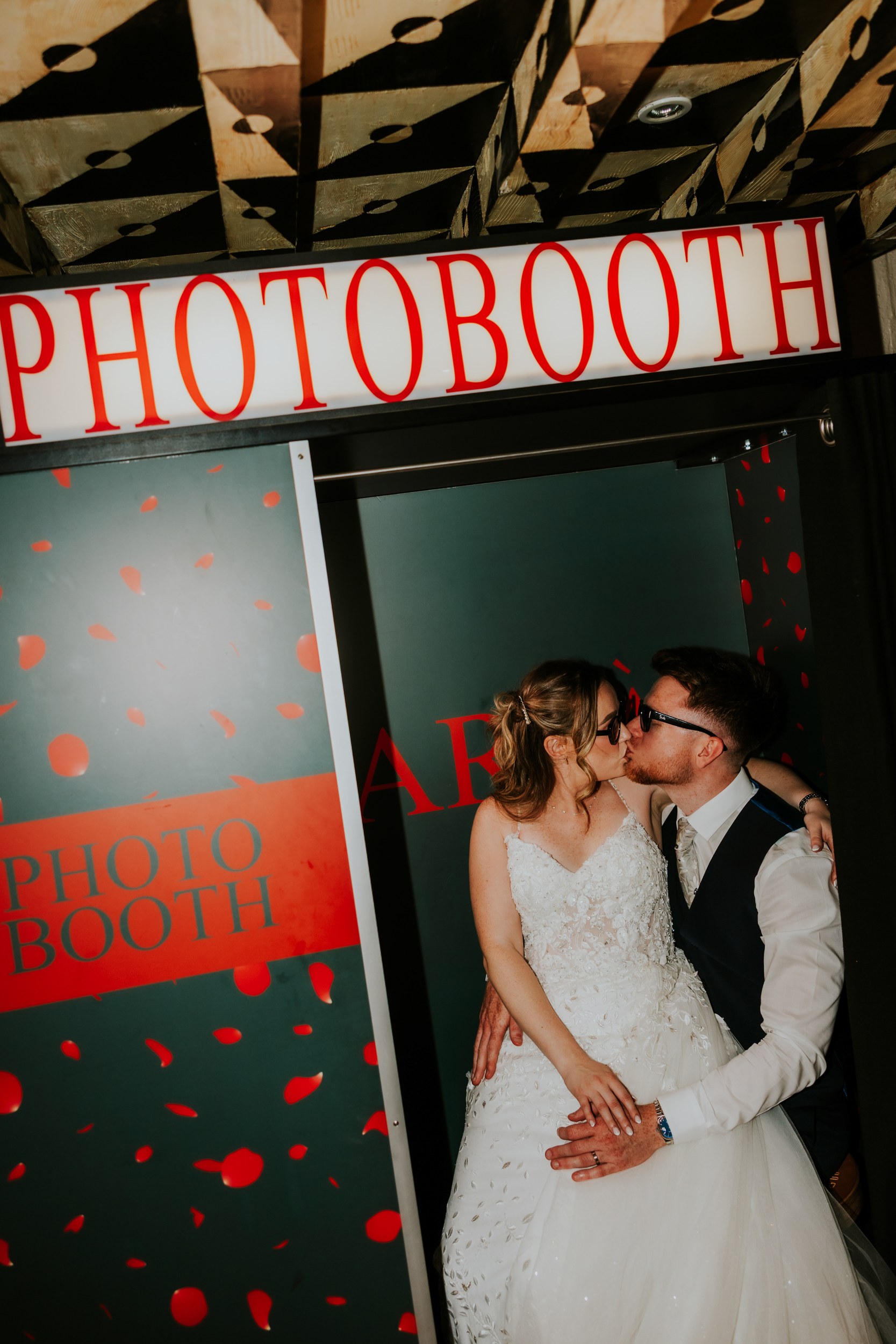Lucy and John wearing sunglasses and kissing in the photo booth at Arta, Glasgow.
