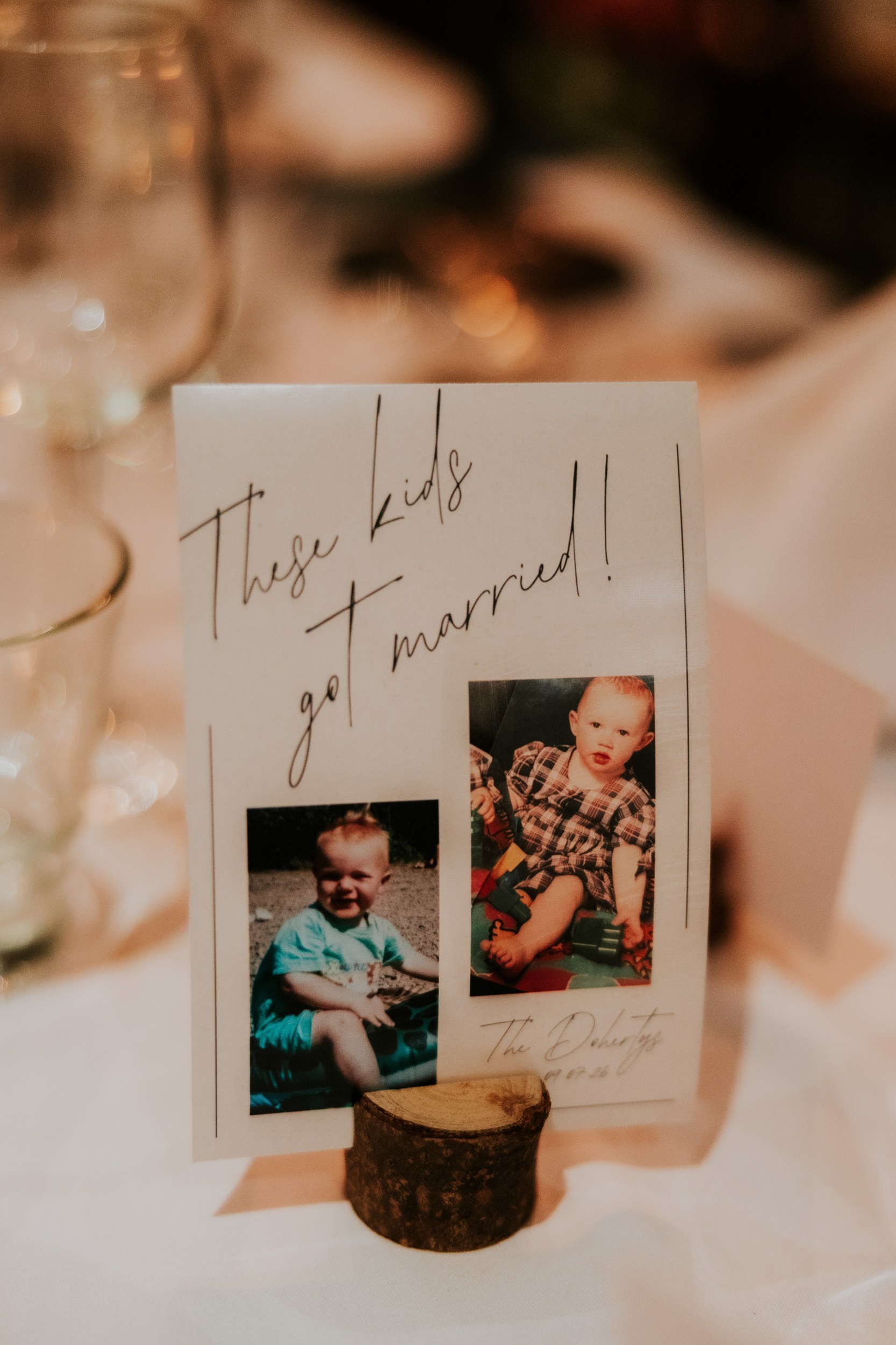 Wedding table card with two childhood photographs and ‘These kids got married!’ in a wooden holder at Arta.