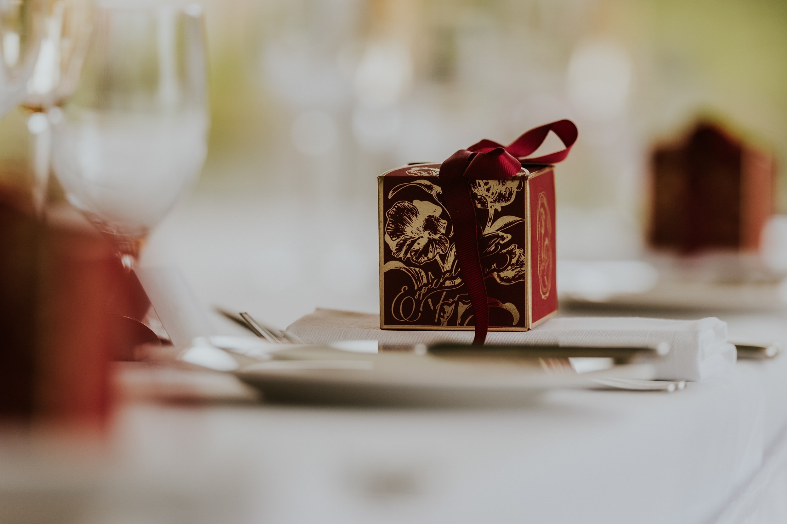 Burgundy and gold wedding favour box with matching ribbon on a white napkin at Lochgreen House Hotel.