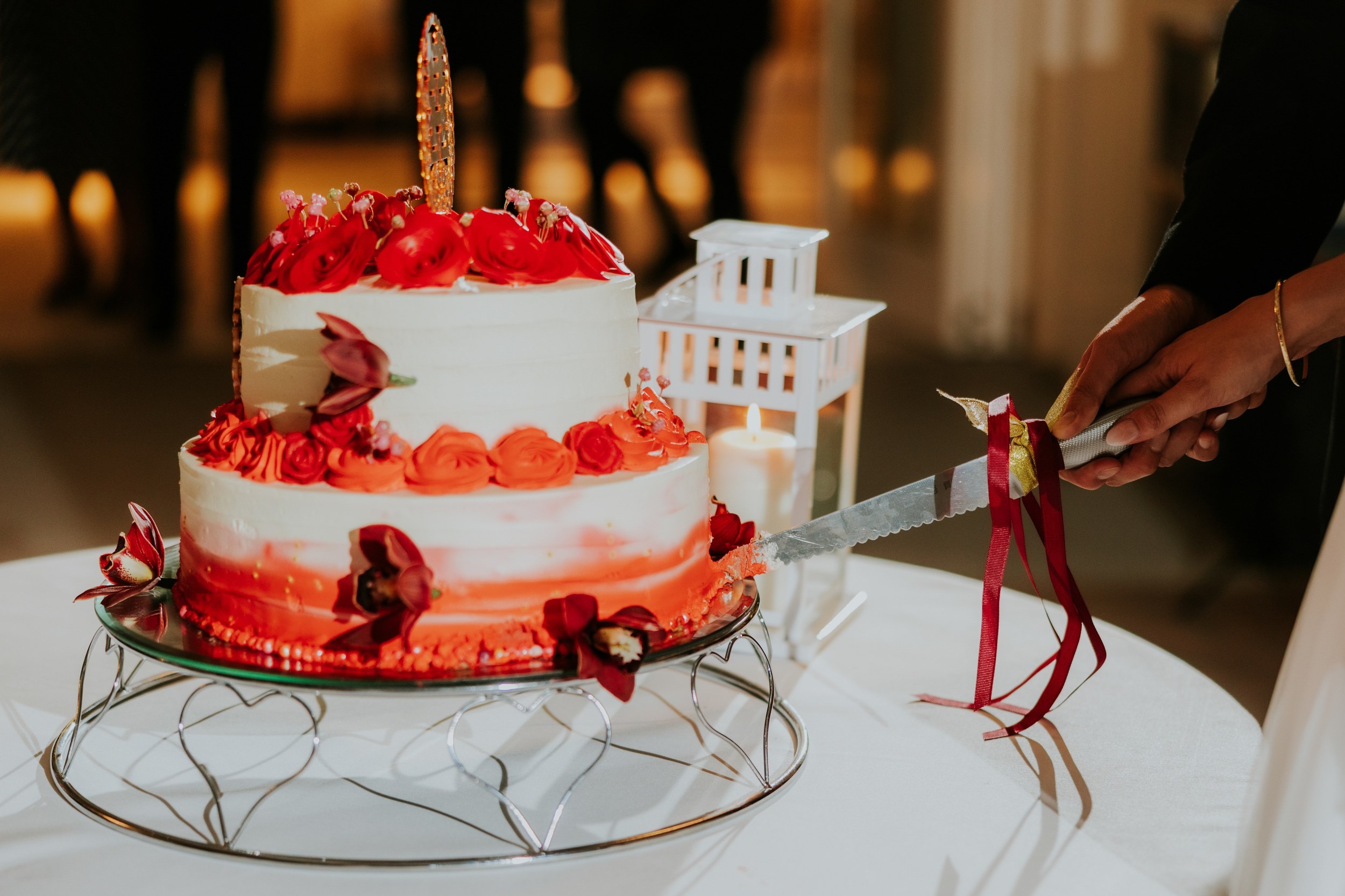 Emma and Gordon cutting their red and orange floral wedding cake at Lochgreen House Hotel.