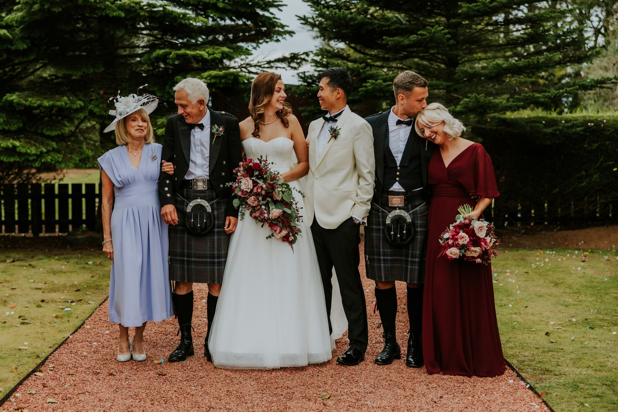 Emma and Gordon smiling with four wedding guests on a garden path at Lochgreen House Hotel.