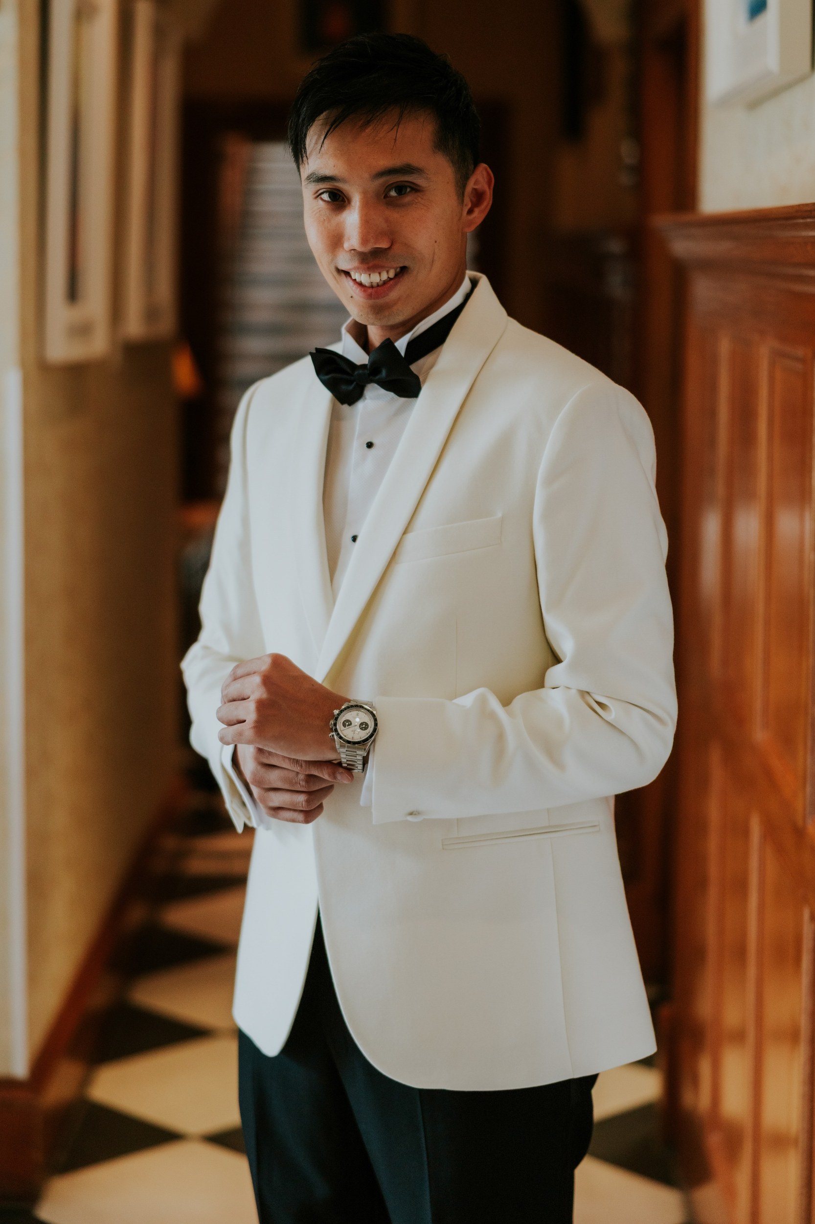 Gordon in an ivory dinner jacket and black bow tie in a wood-panelled corridor at Lochgreen House Hotel.