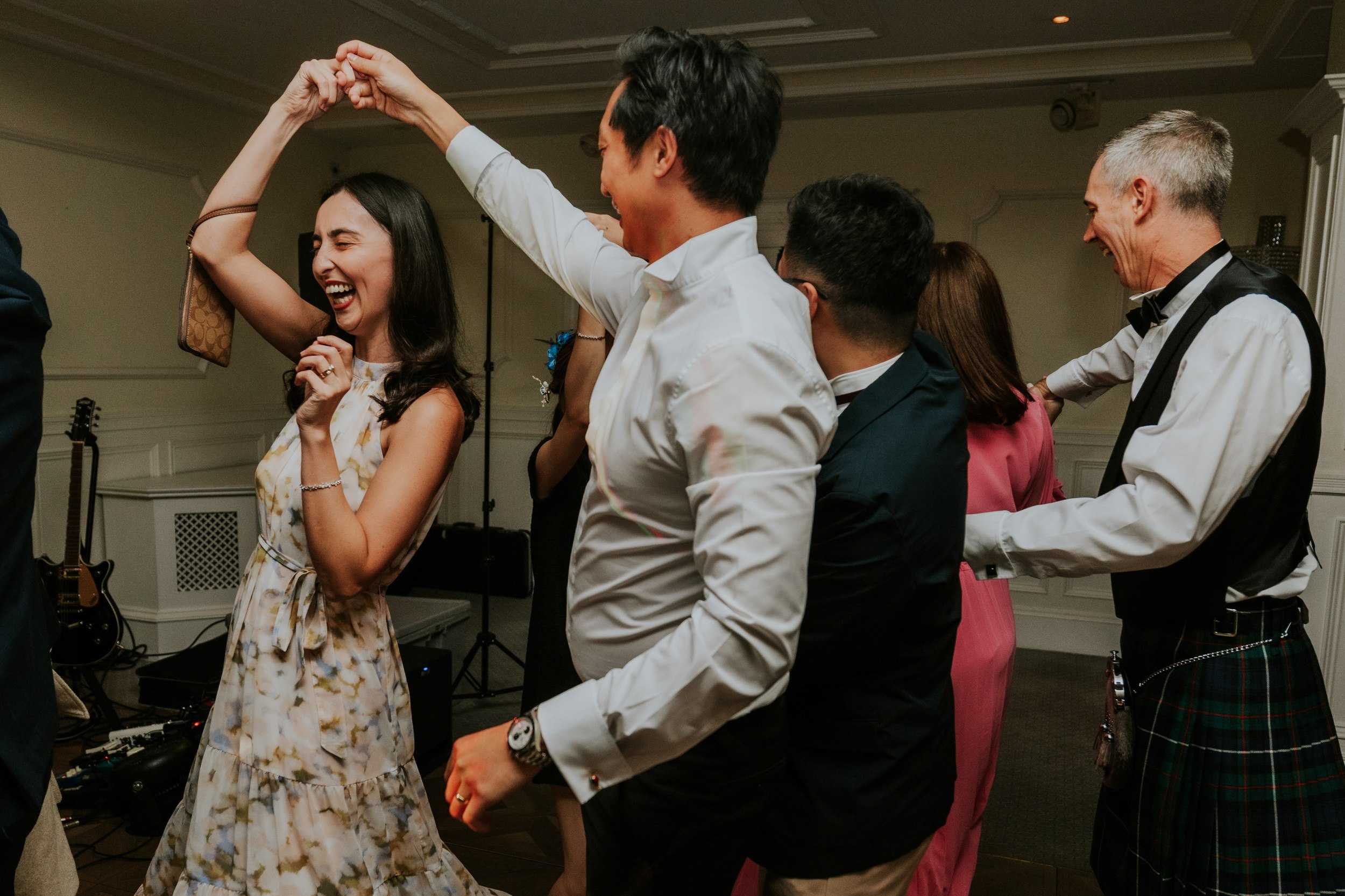 Wedding guests dancing at Lochgreen House Hotel, with a laughing woman twirling beneath her partner's raised hand.