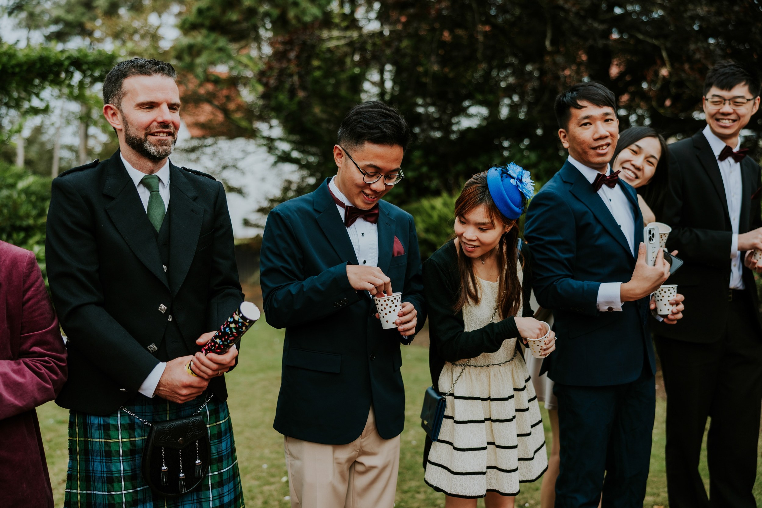 Wedding guests preparing confetti on the lawn at Lochgreen House Hotel, with paper cups and a confetti cannon.